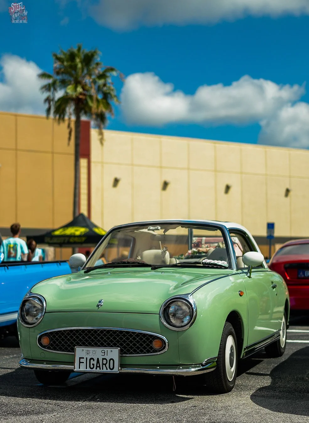 Light green Nissan Figaro with a white roof and chrome accents on display at a Dezerland Park Orlando car event.