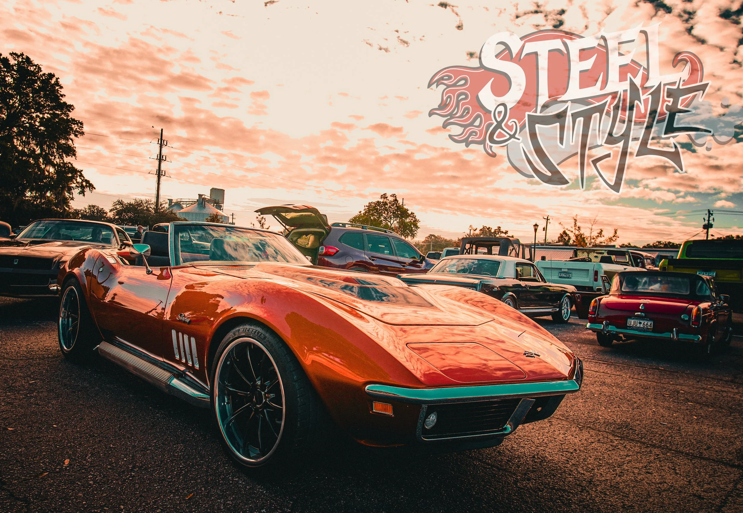 A vintage red Chevrolet Corvette parked among other classic and modern cars at a car show during sunset.