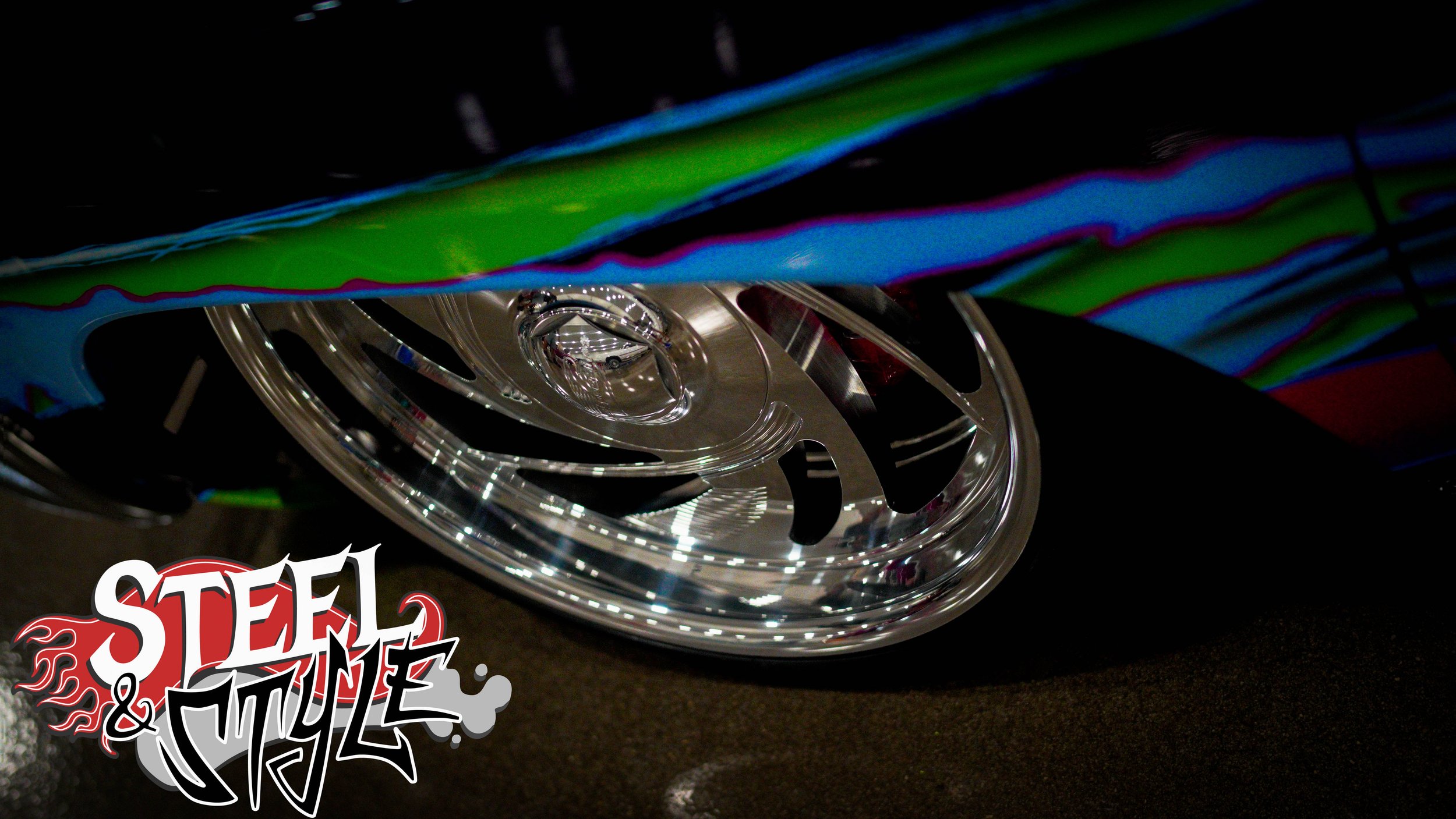 Close-up of a shiny chrome car wheel with a colorful, reflective paint design above it, and a stylized 'Steel & Style' logo in the bottom left corner.