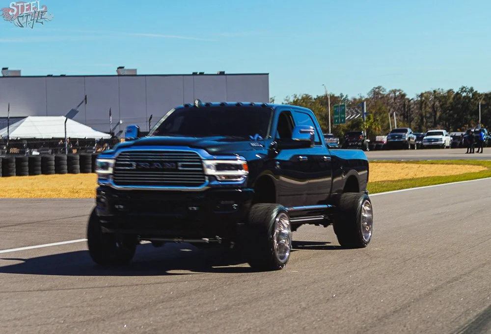 A black pickup truck with oversized wheels on a racing track.