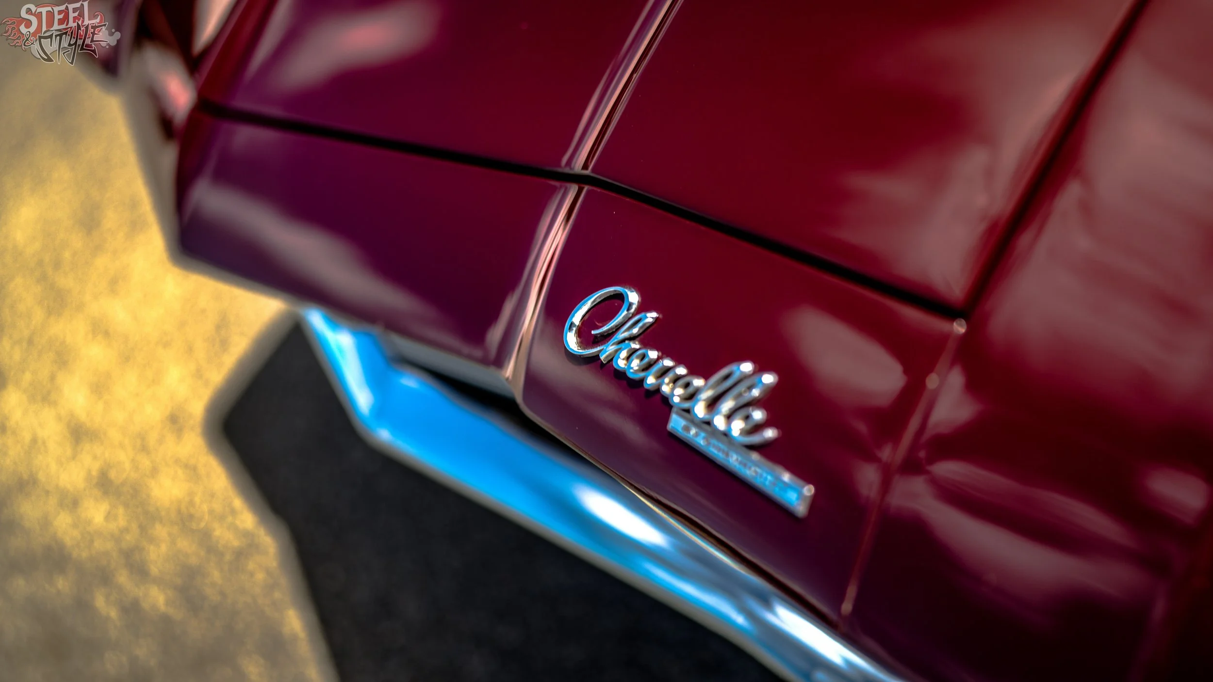 Close-up of a maroon Chrysler vehicle with chrome Chrysler emblem on the rear.