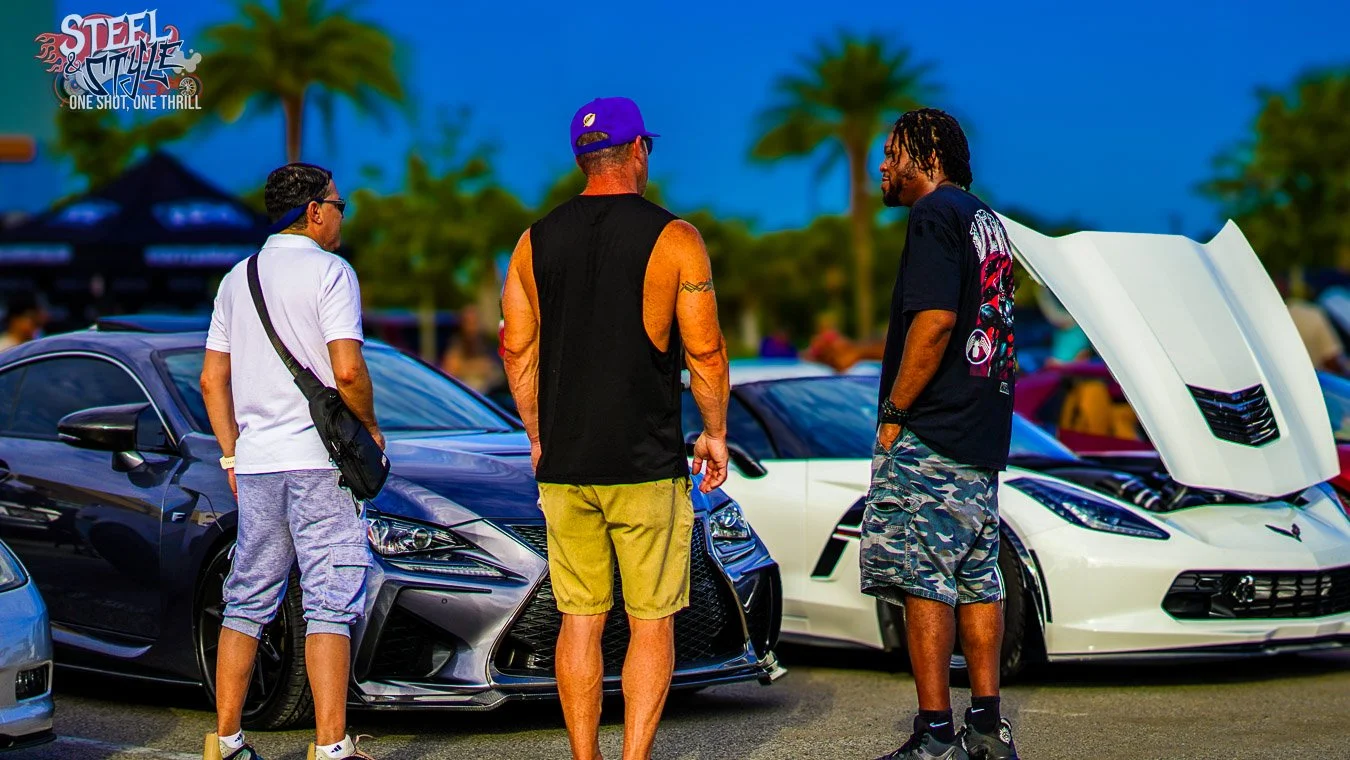 Spectators enjoying conversation in front of a row of cars.