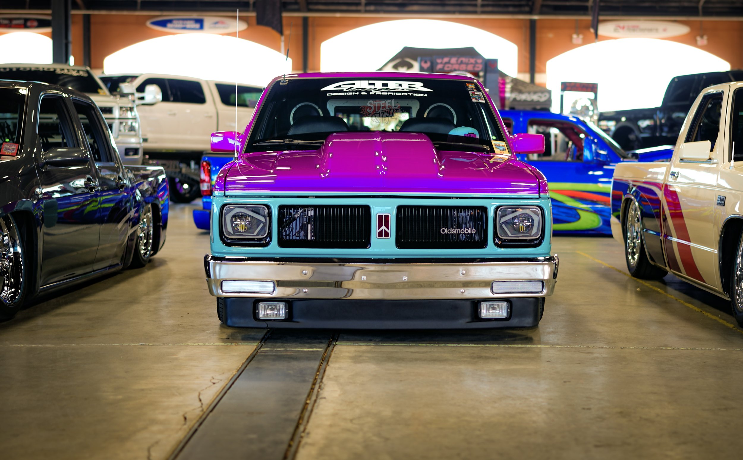Colorful vintage pickup truck at a car show with other classic trucks around it.