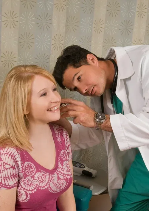 A healthcare worker administering a vaccination to a man sitting on a stool.