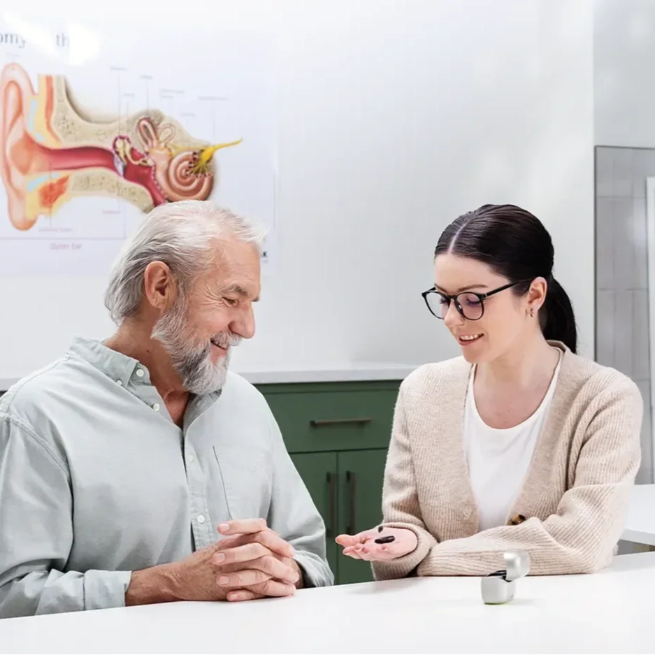 A medical professional presenting a hearing aid to an older gentleman