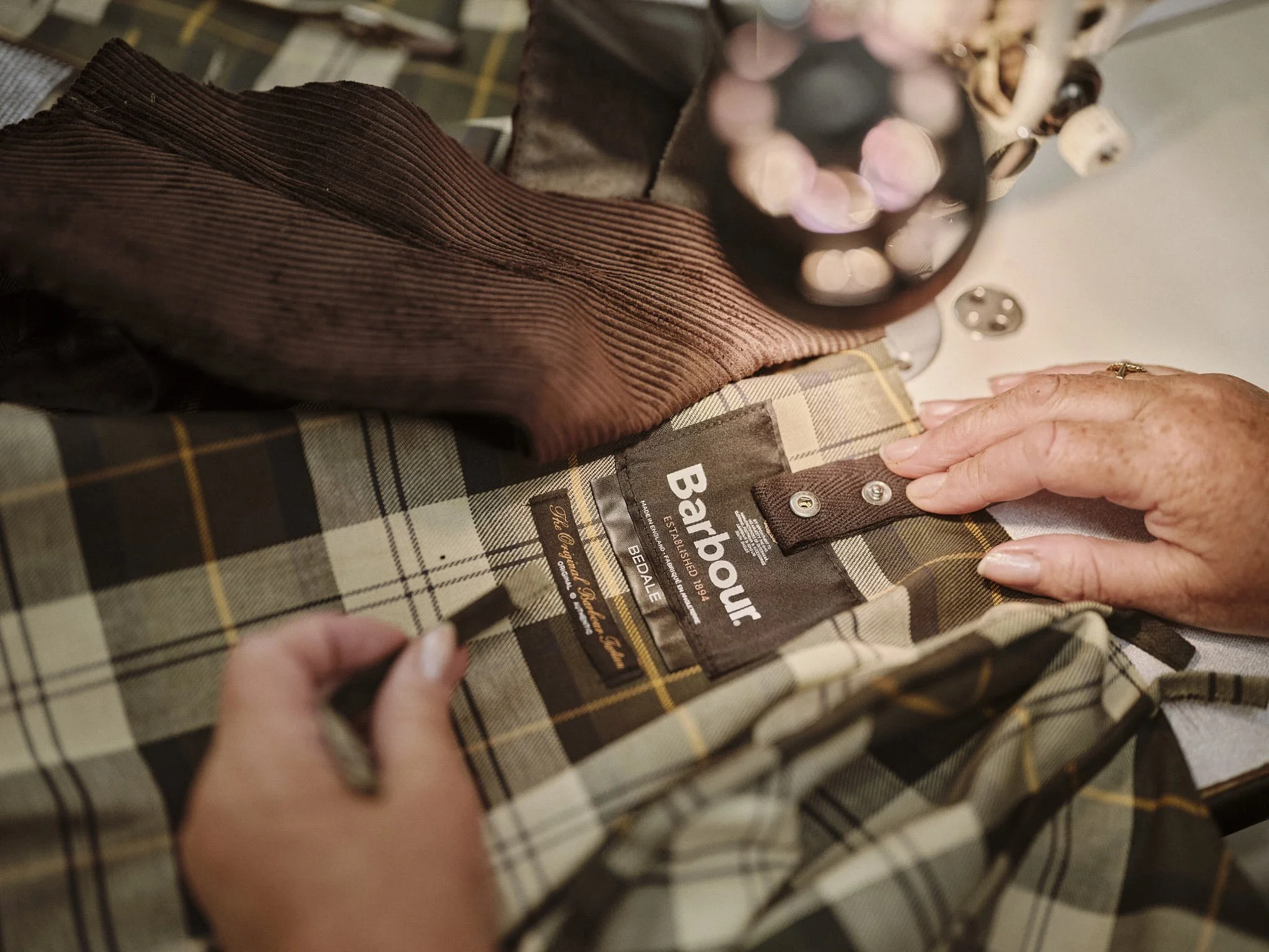 Barrbour - A factory worker is sewing a Barbour label 1.jpg