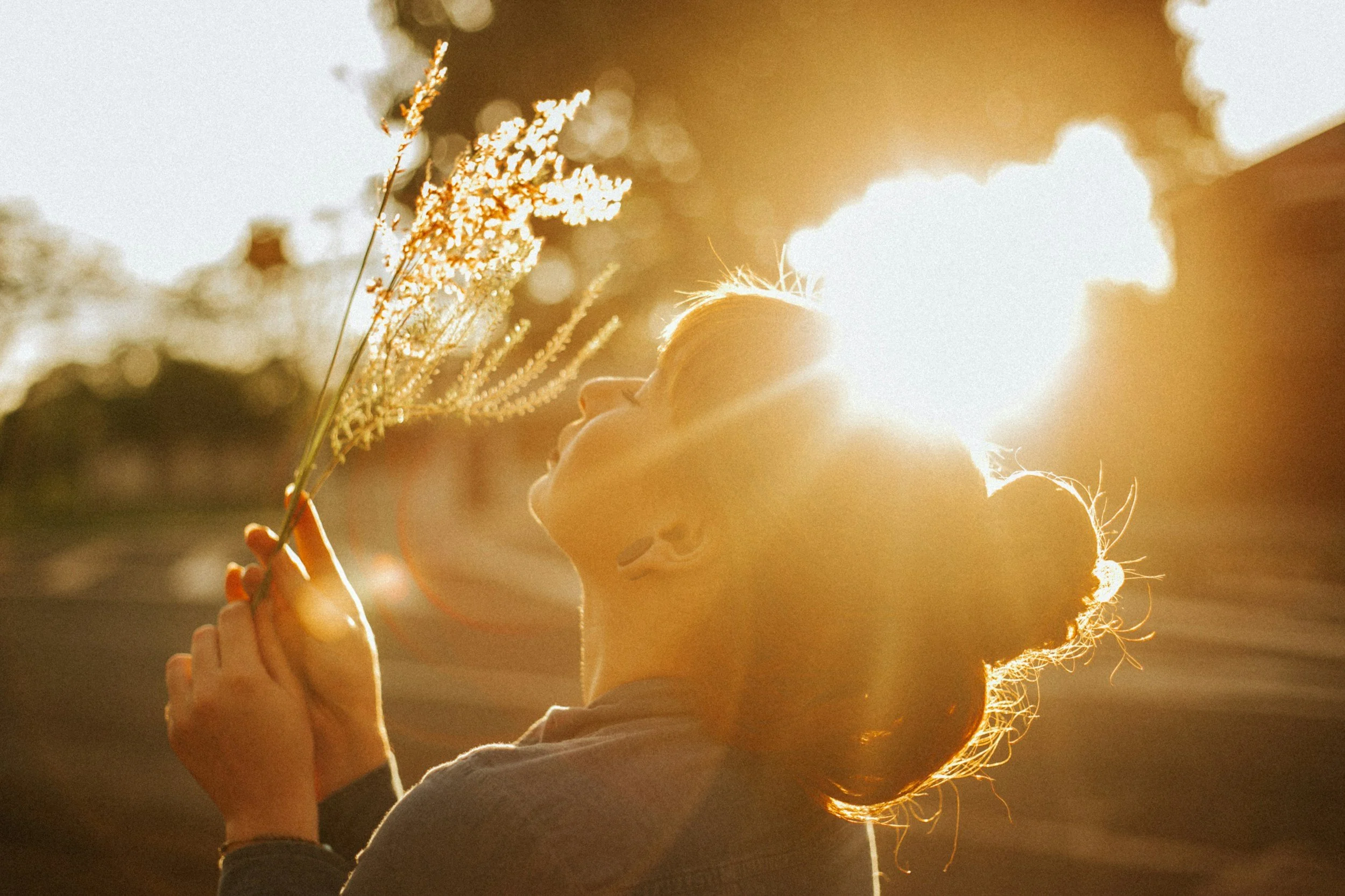 Smiling peaceful happy woman holding flowers in the sunlight.