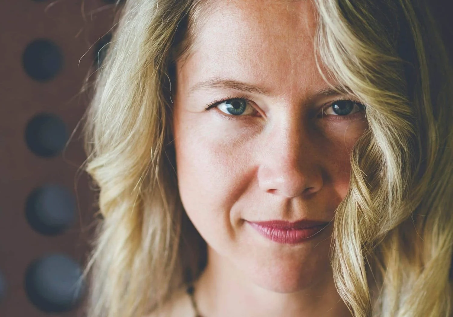 Close-up of a woman with blonde hair and blue eyes, smiling gently.