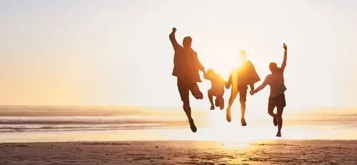 Four people jumping on the beach during sunset