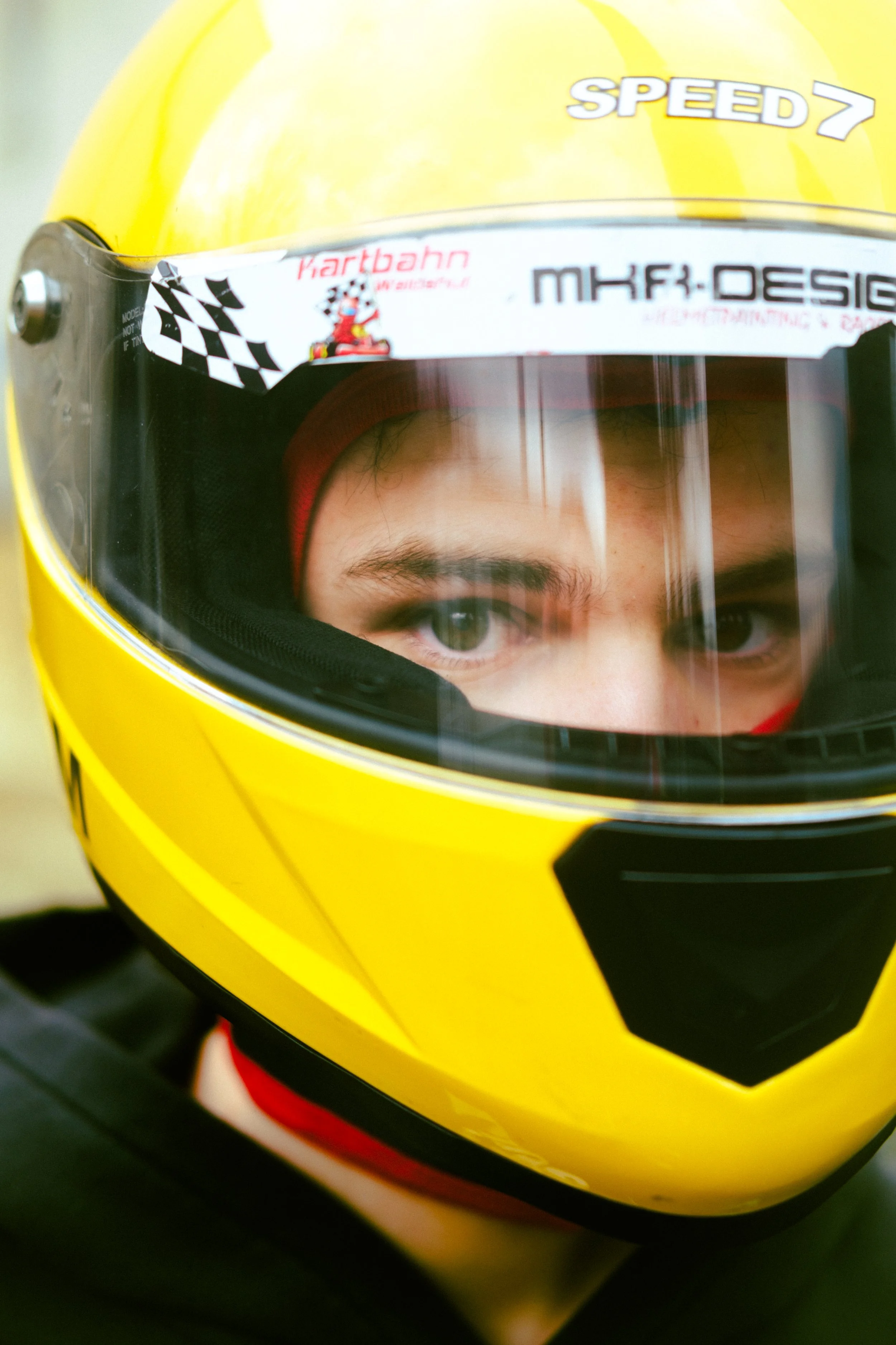 Nahaufnahme eines Rennfahrers im gelben Helm, der in den Visier schaut.