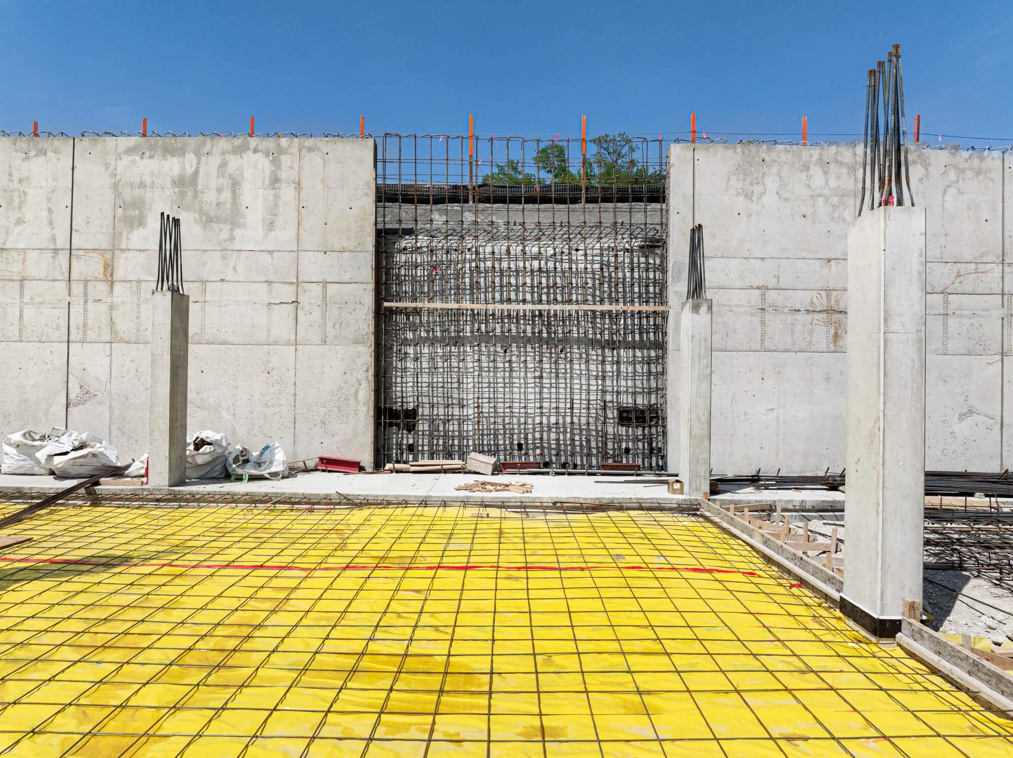 Rebar reinforcement and vapor barrier prepared for concrete slab and wall pour at commercial construction project in Texas