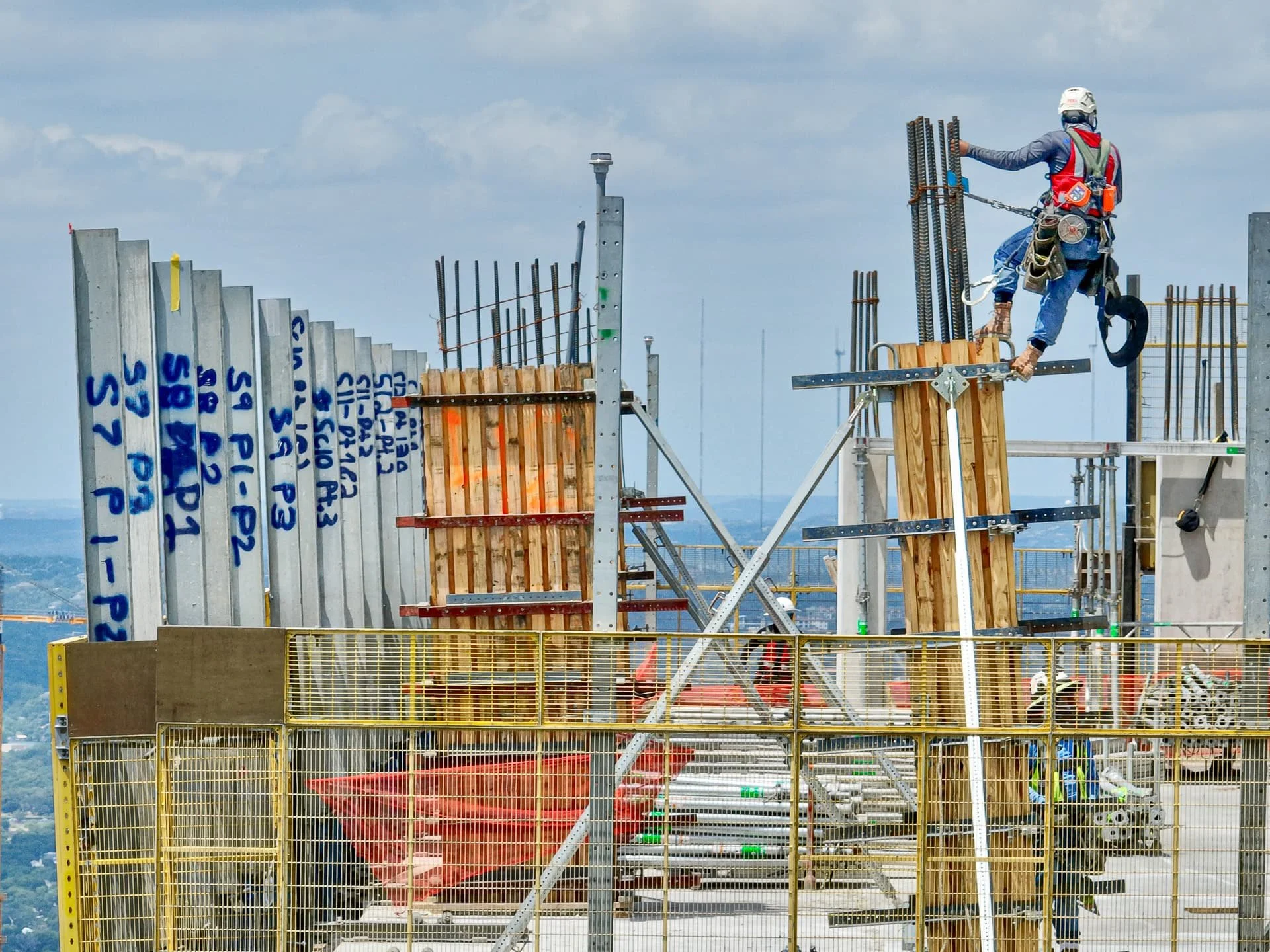 Construction worker with personal fall arrest system installing rebar on high-rise skyscraper in downtown Gaston Cherry drone photographer