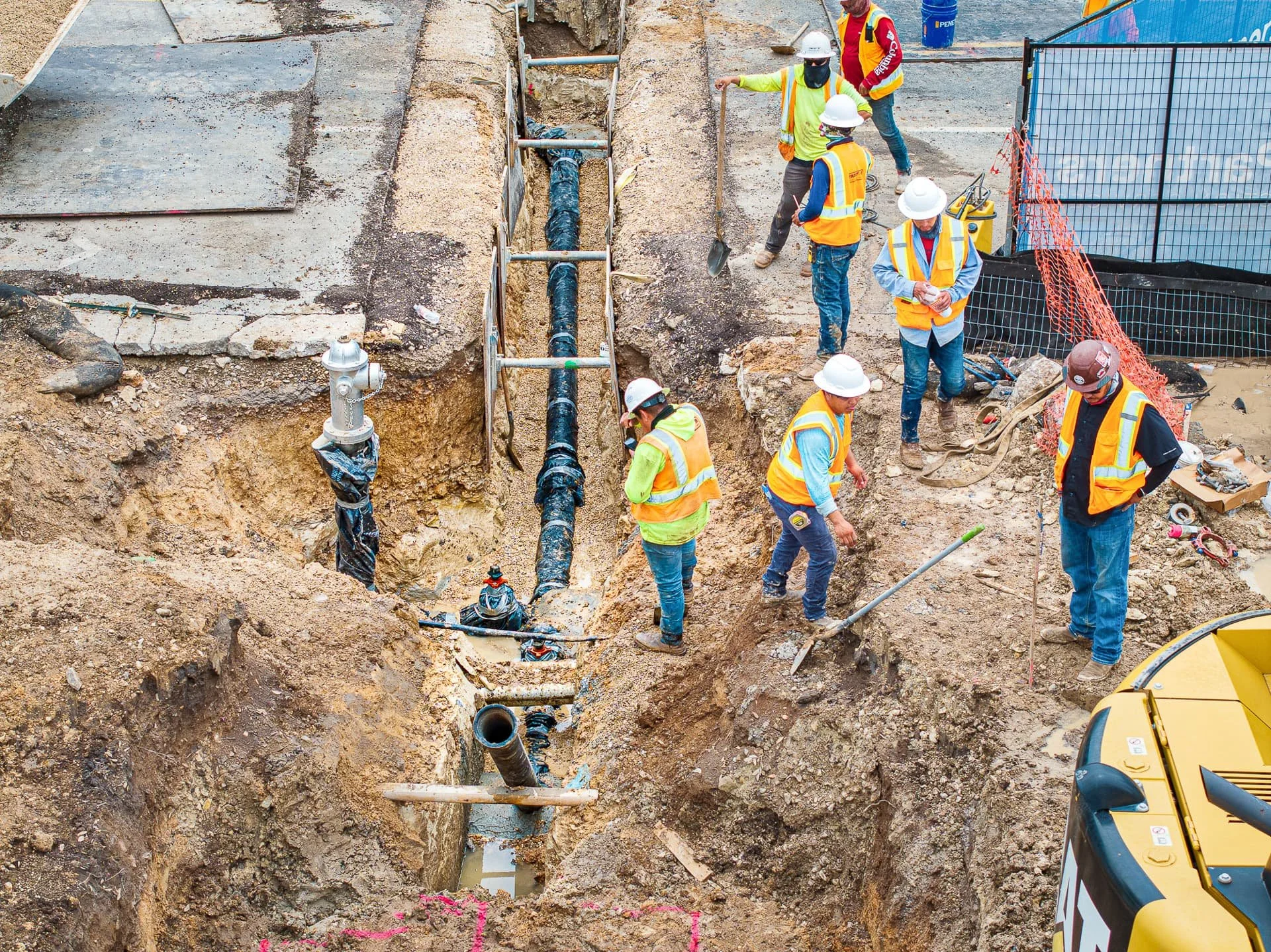 Construction crew installing underground water line in reinforced trench at utility project site in Austin, Texas
