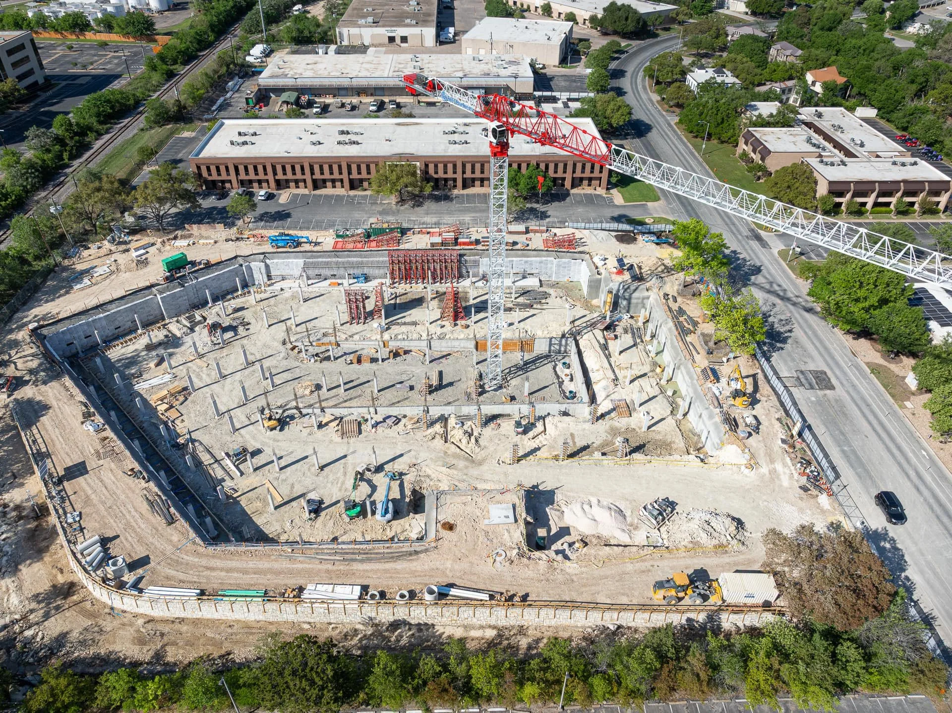 Drone aerial photo of foundation excavation with tower crane and column forms at OHT Partners construction site in Austin.