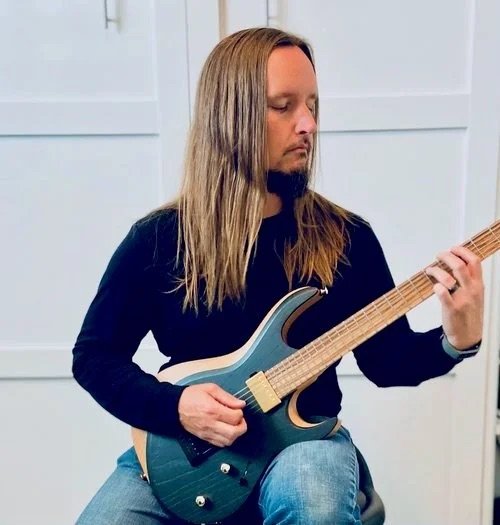 John H. teaches guitar and bass at the Wylie School of Music. Pictured here with a guitar.