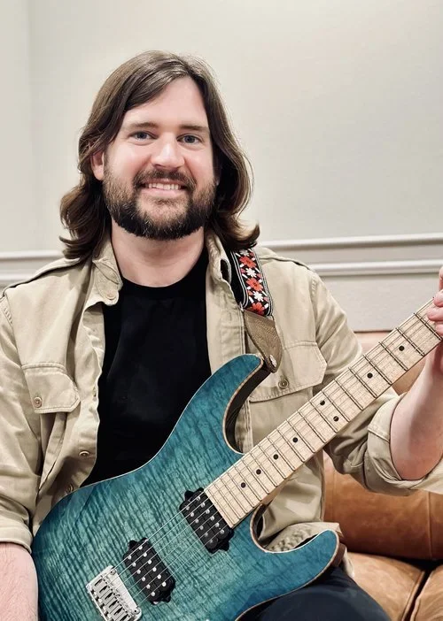 Doug teaches guitar and bass at the Wylie School of Music. Pictured here with a guitar.