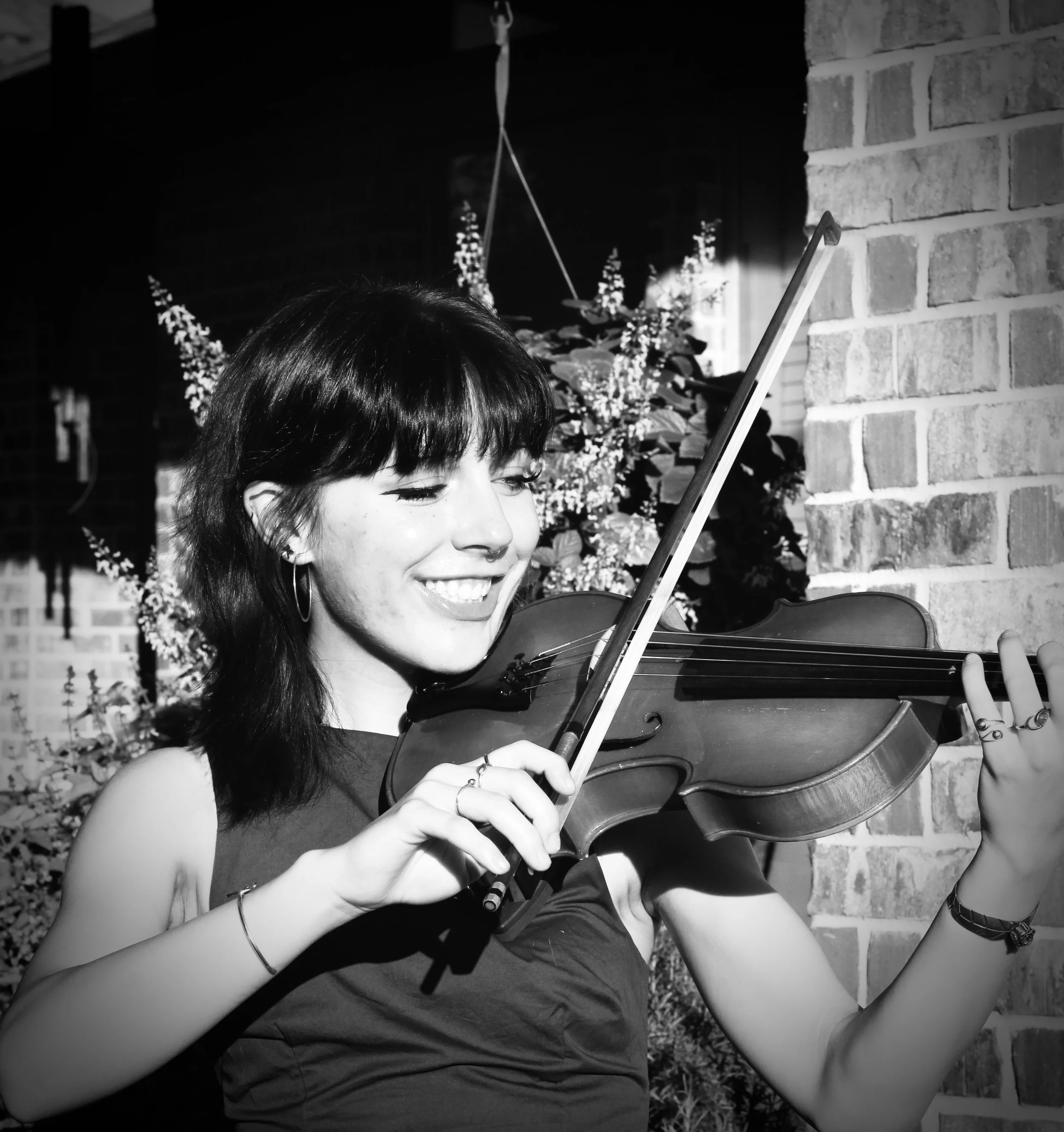 Lillian teaches piano and beginner guitar at the Wylie School of Music. The photo shows her smiling while she plays the violin.