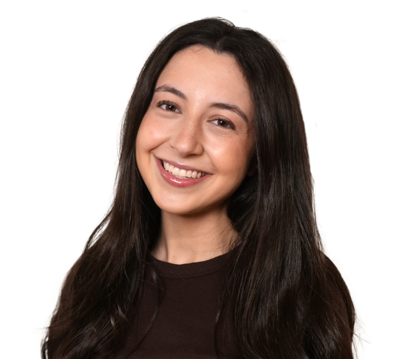 Portrait of a woman with long dark hair and a white sweater, against a light background.