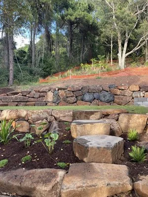 Terraced garden with stone steps and walls, plants, and trees in the background.