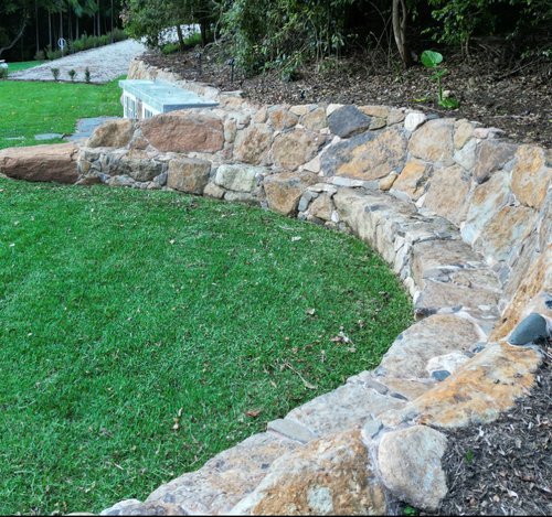 Curved stone retaining wall with grass lawn