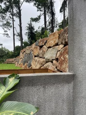 Outdoor stacked stone wall with lush greenery and trees in the background