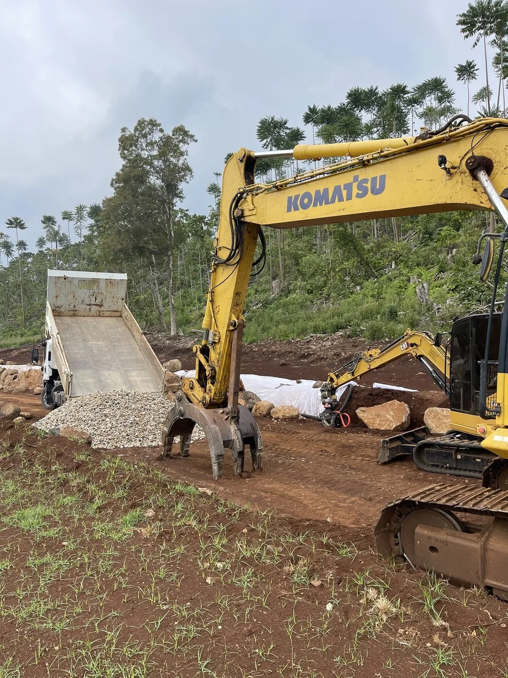 Construction site with excavator and dump truck unloading gravel
