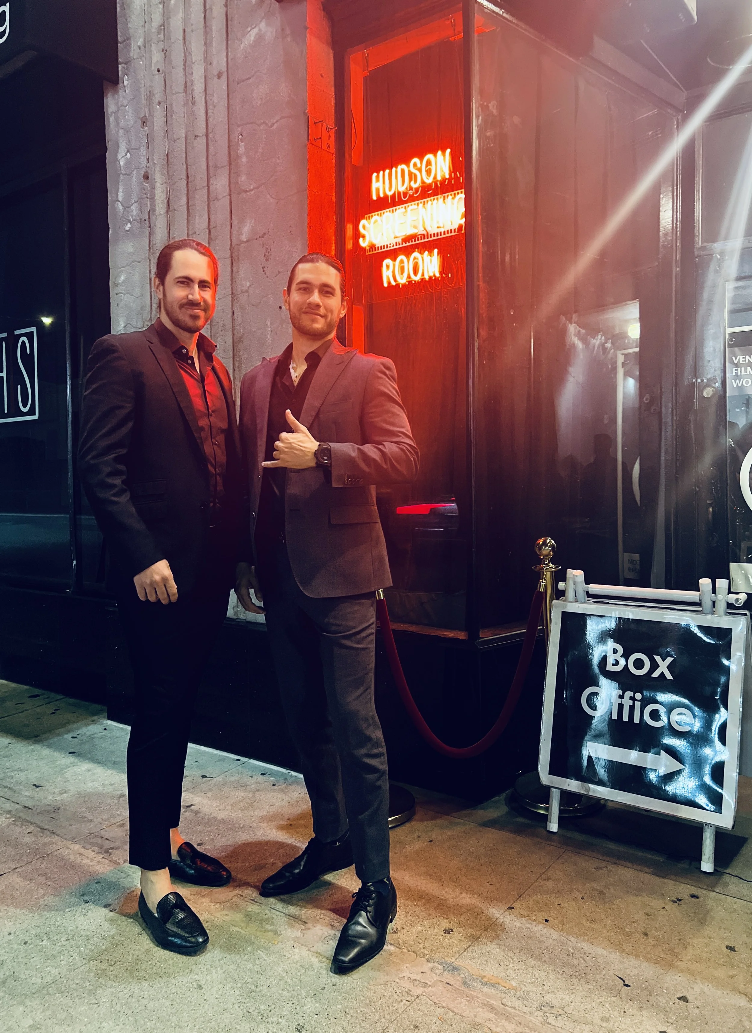 Axel Axe and CJ Axe standing outside a The Hudson Theater box office during the premiere of their film RESCUE.