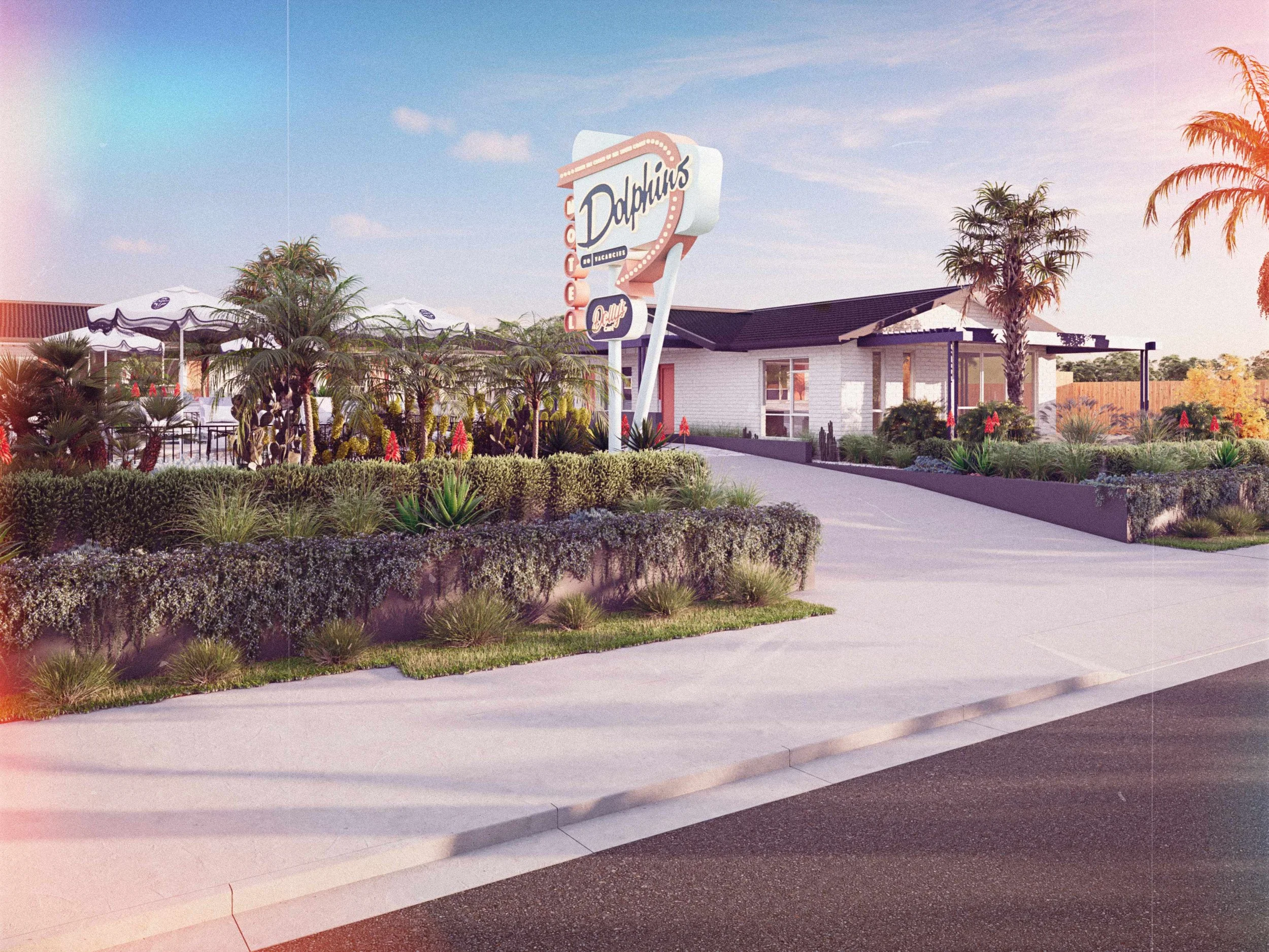 Exterior of a retro-style diner with a neon sign reading "Dolphins" and an outdoor seating area with umbrellas, surrounded by desert plants and palm trees.