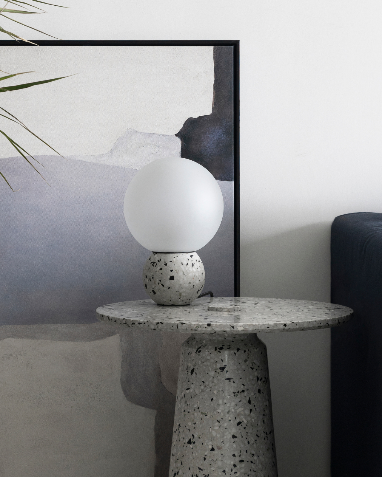 White Terrazzo Table Lamp in front of a painting on a console side table in a living room