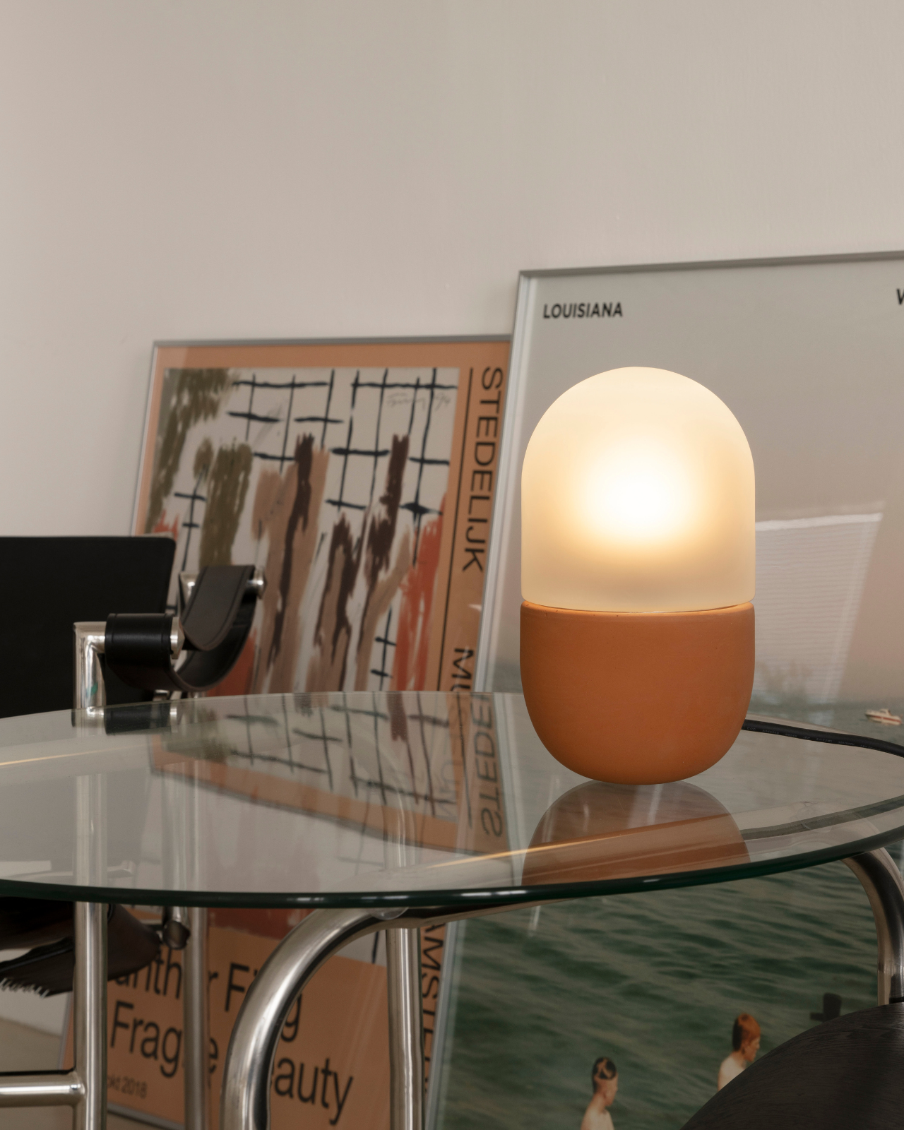 Cast Earth Table Lamp on a glass table illuminating a living room with art behind