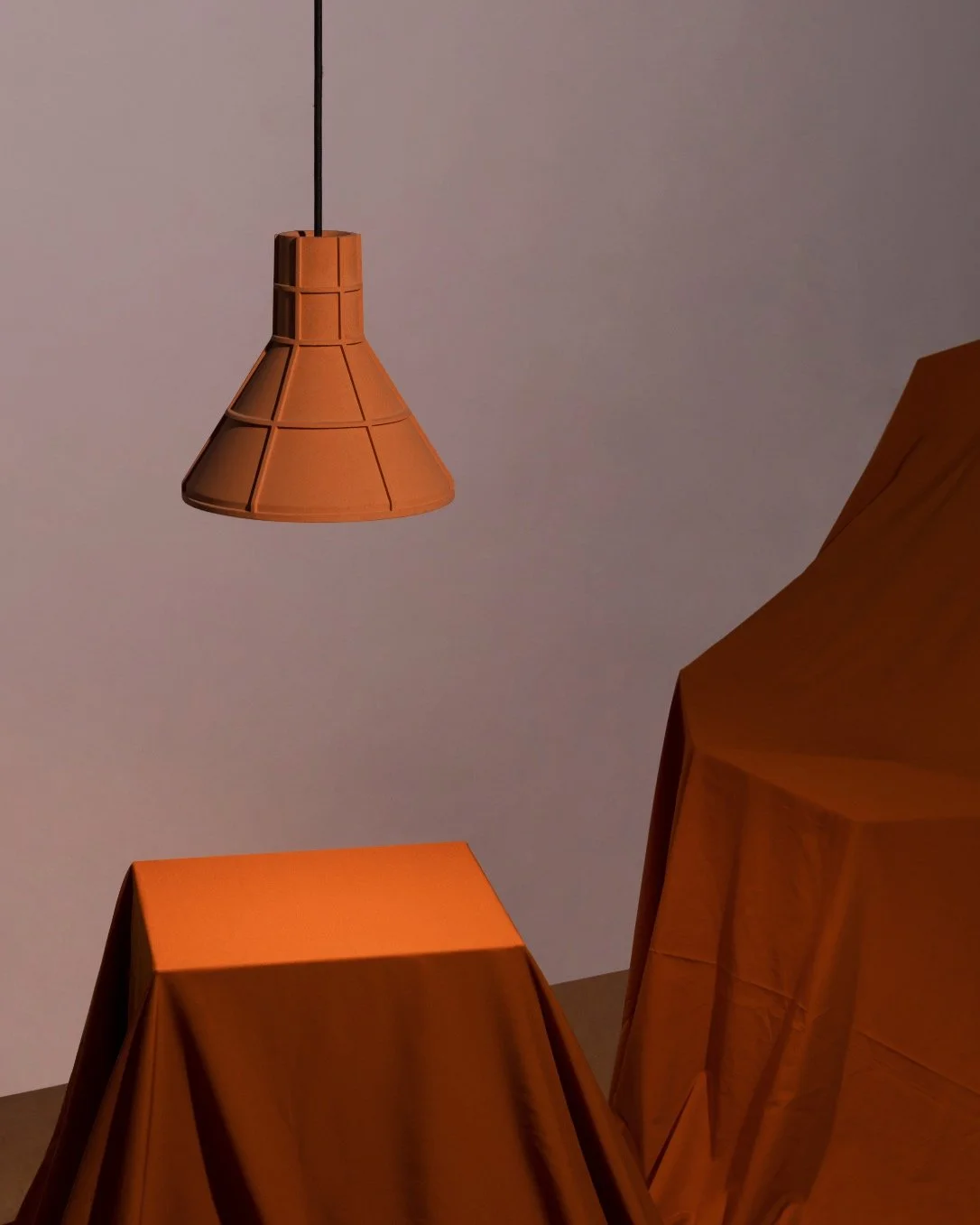 Orange Cast Earth Pendant Light hanging above an orange sheet covered plinth