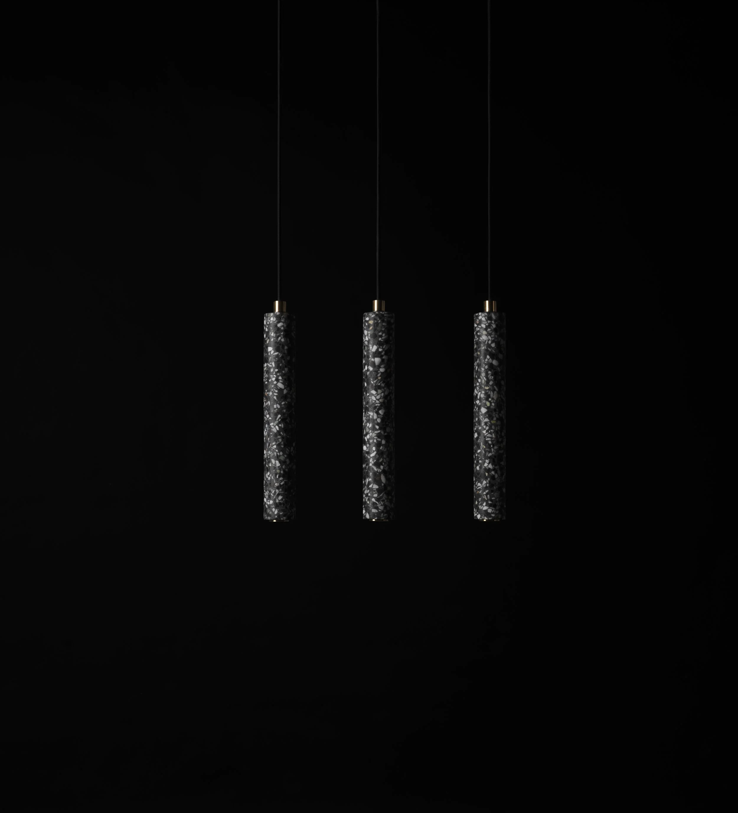 Three Black Terrazzo Stone Pendants in a dark room