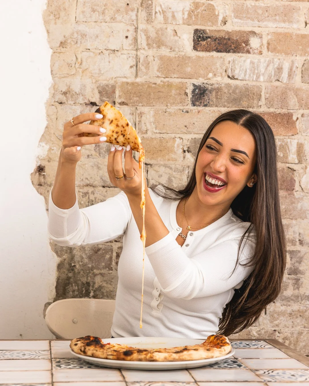 Girl enjoying wood-fired cheesy pizza at Sydney Italian restaurant