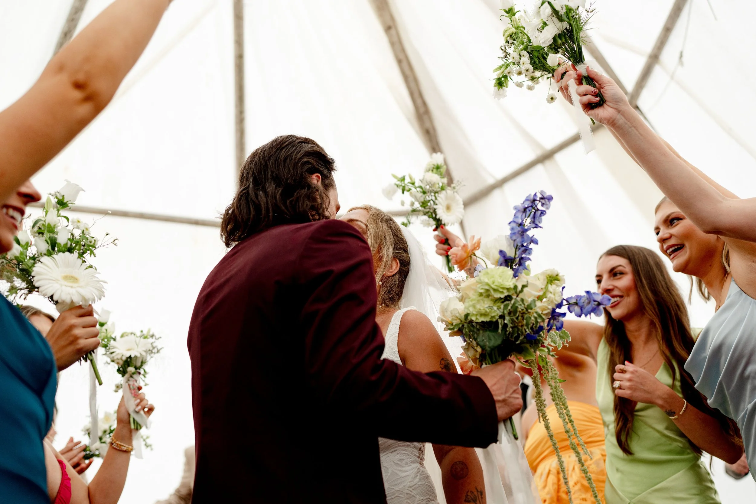 happy couple kissing at their wedding surrounded by bouquets of flowers