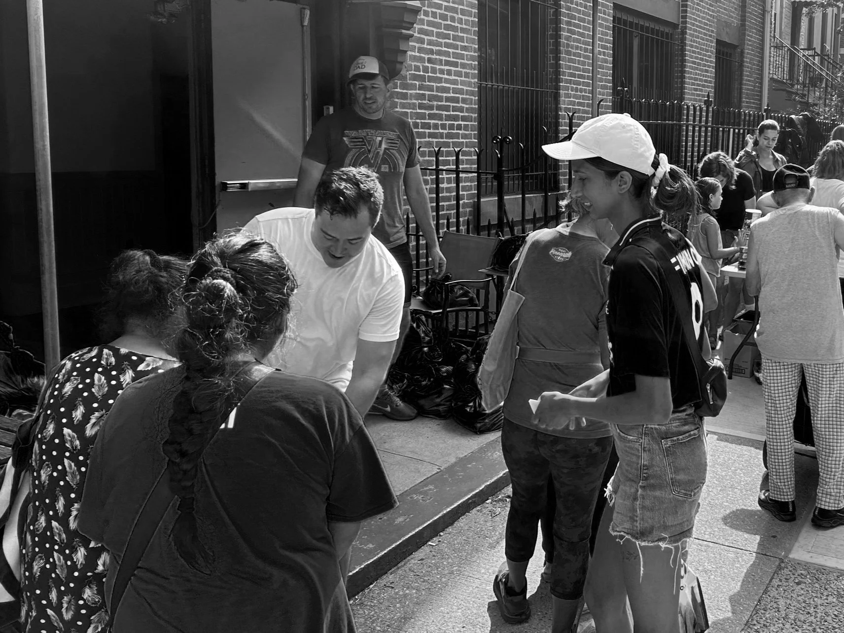 Group of people distributing food outdoors, brick building, community event.