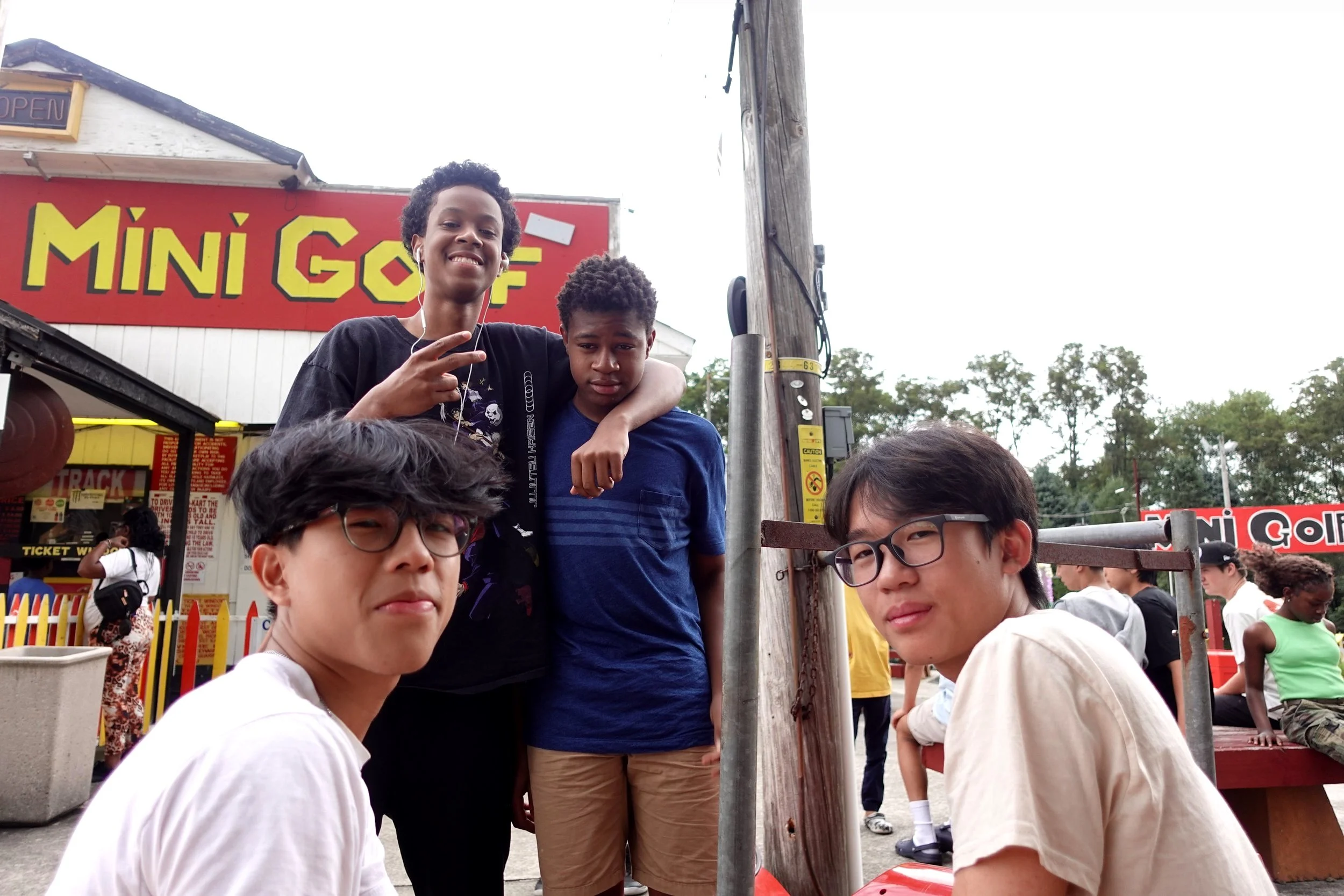 Group of four young people posing in front of a mini golf sign outdoors