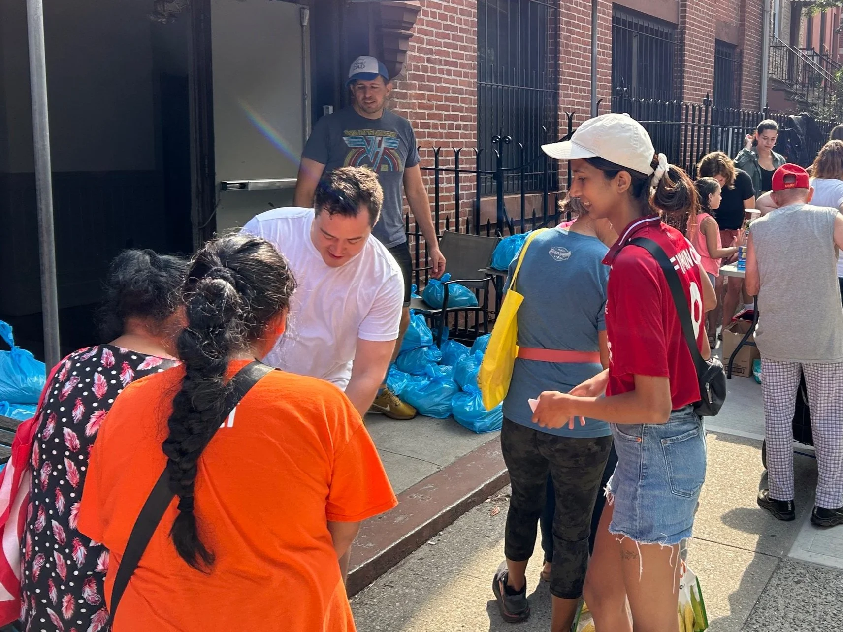 A group of people engaged in handing out goods from a building entrance on a city street.