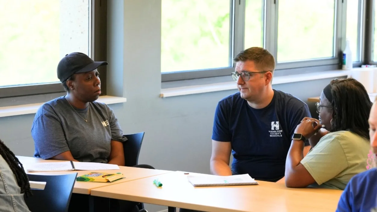 Picture of white man in glasses talking to a black women in a hat about well being and burnout