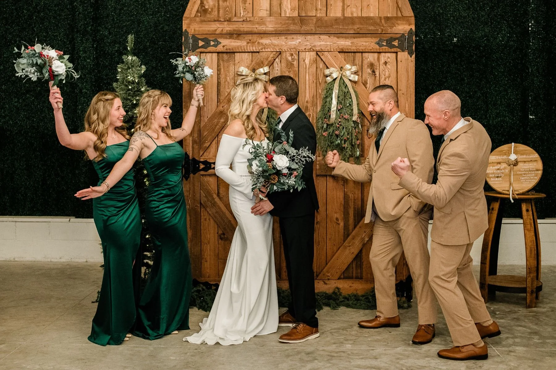 joyful winter wedding party photo in front of rustic door