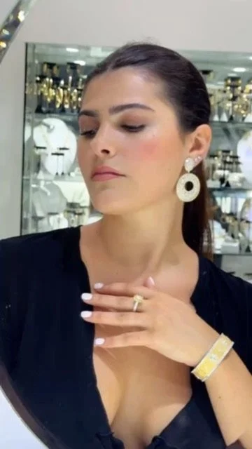 Inside the shop. Dangle earrings, a ring with a large yellow stone, and a wide yellow gold bangle.