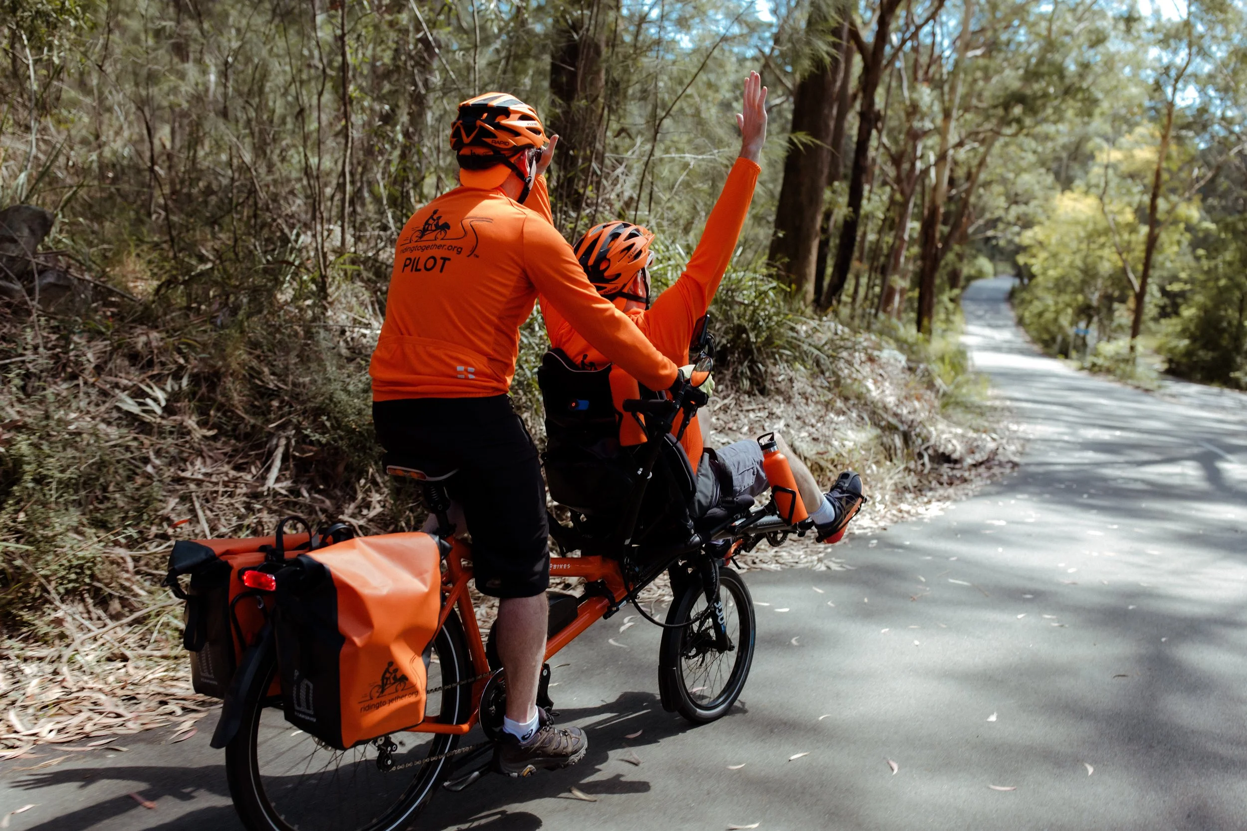 The front rider raises an arm on the descent while the pilot steers behind