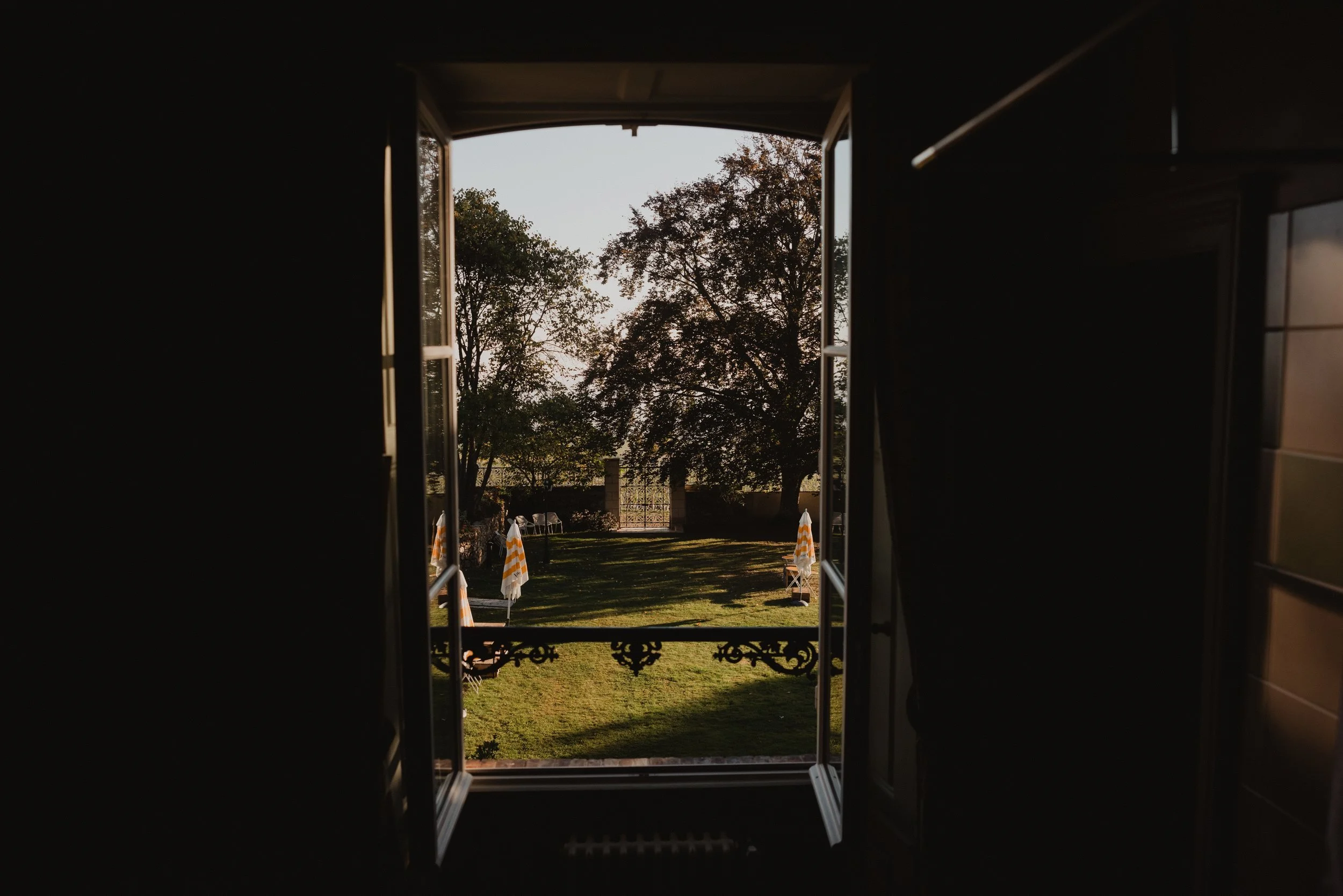 A dark room frames an open doorway onto the garden lawn and trees.