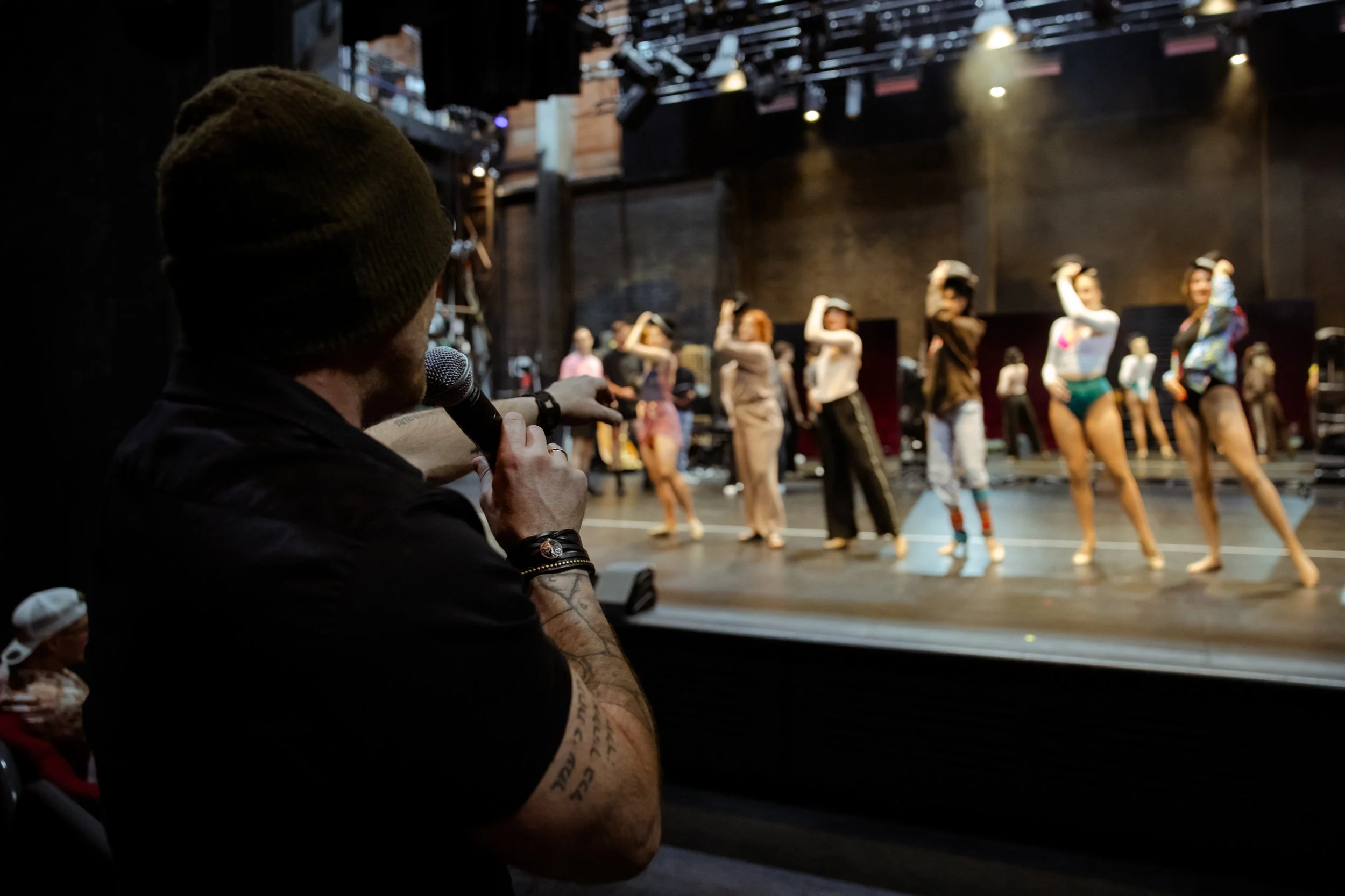 The director watching rehearsal from the house while the cast works on stage