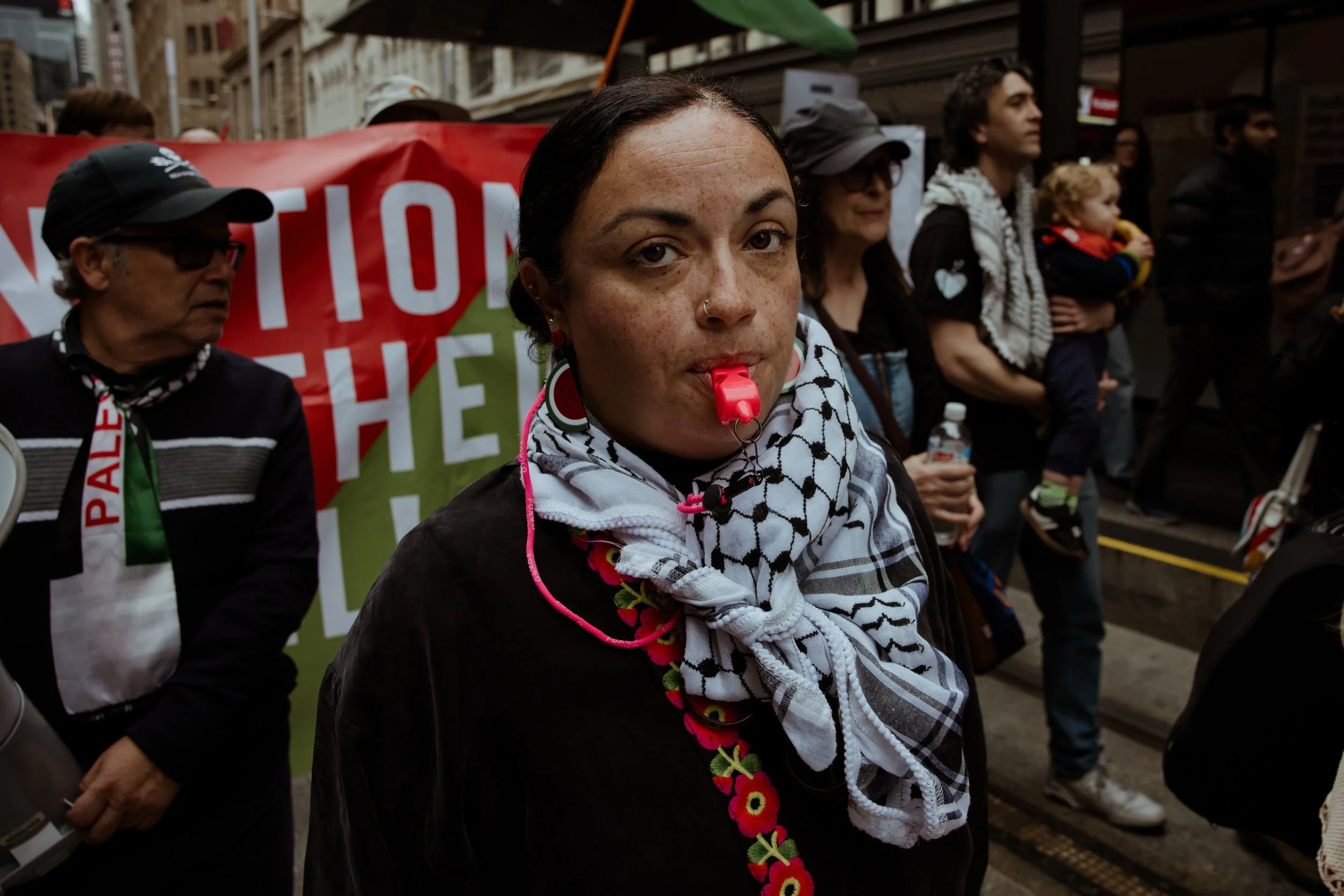 A woman with a whistle in front of a red banner