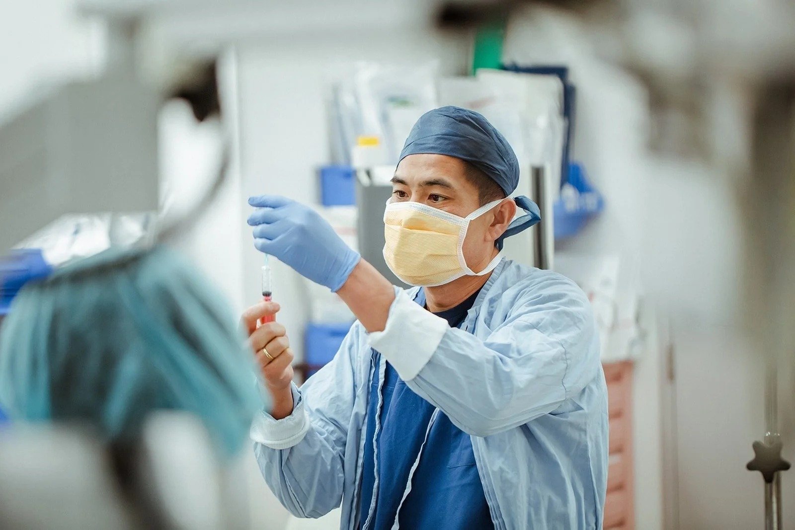 A surgeon in a cap and mask preparing a syringe at Gosford Private Hospital