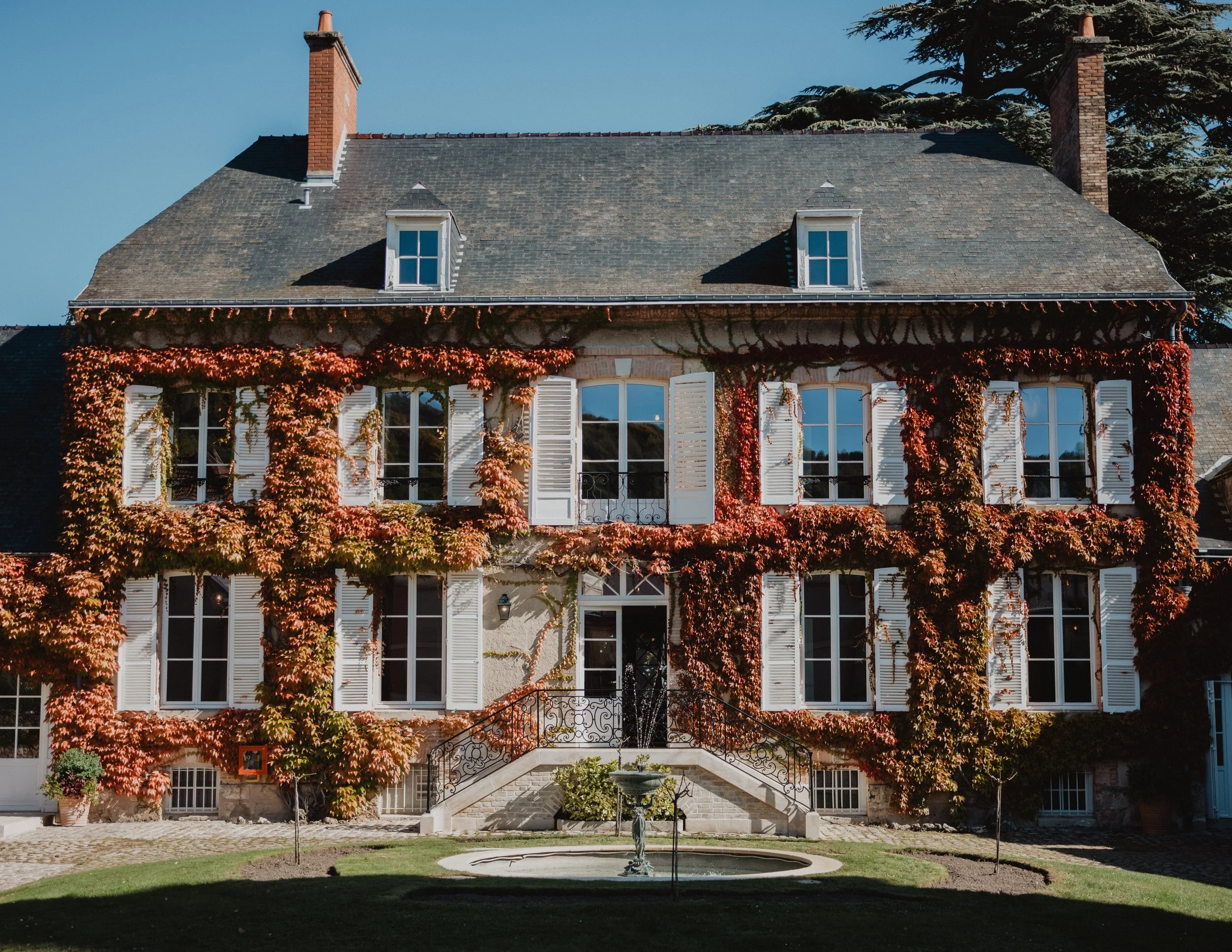 The ivy-red facade of Manoir de Verzy above its courtyard fountain.