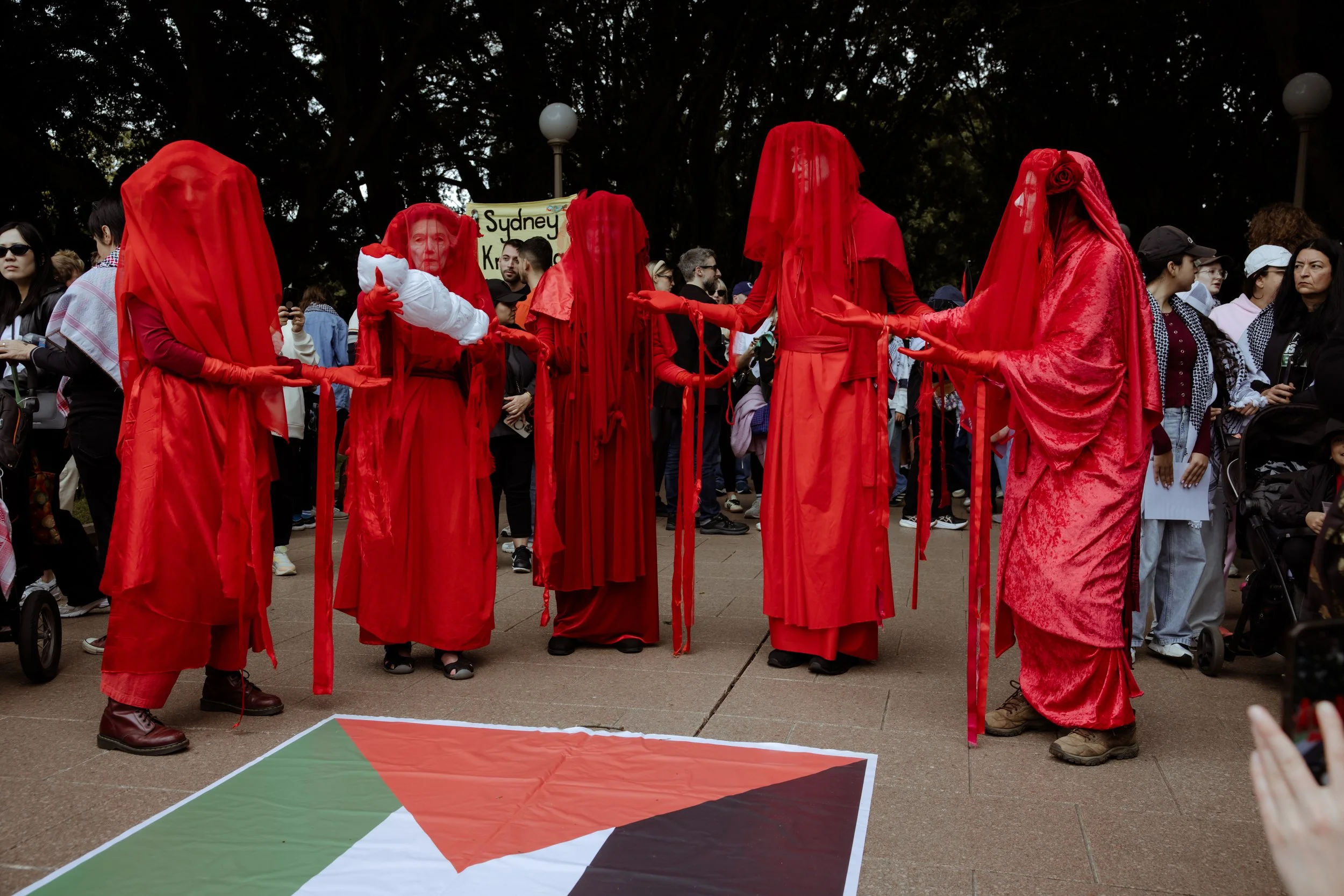 Performers in red robes crossing a painted flag