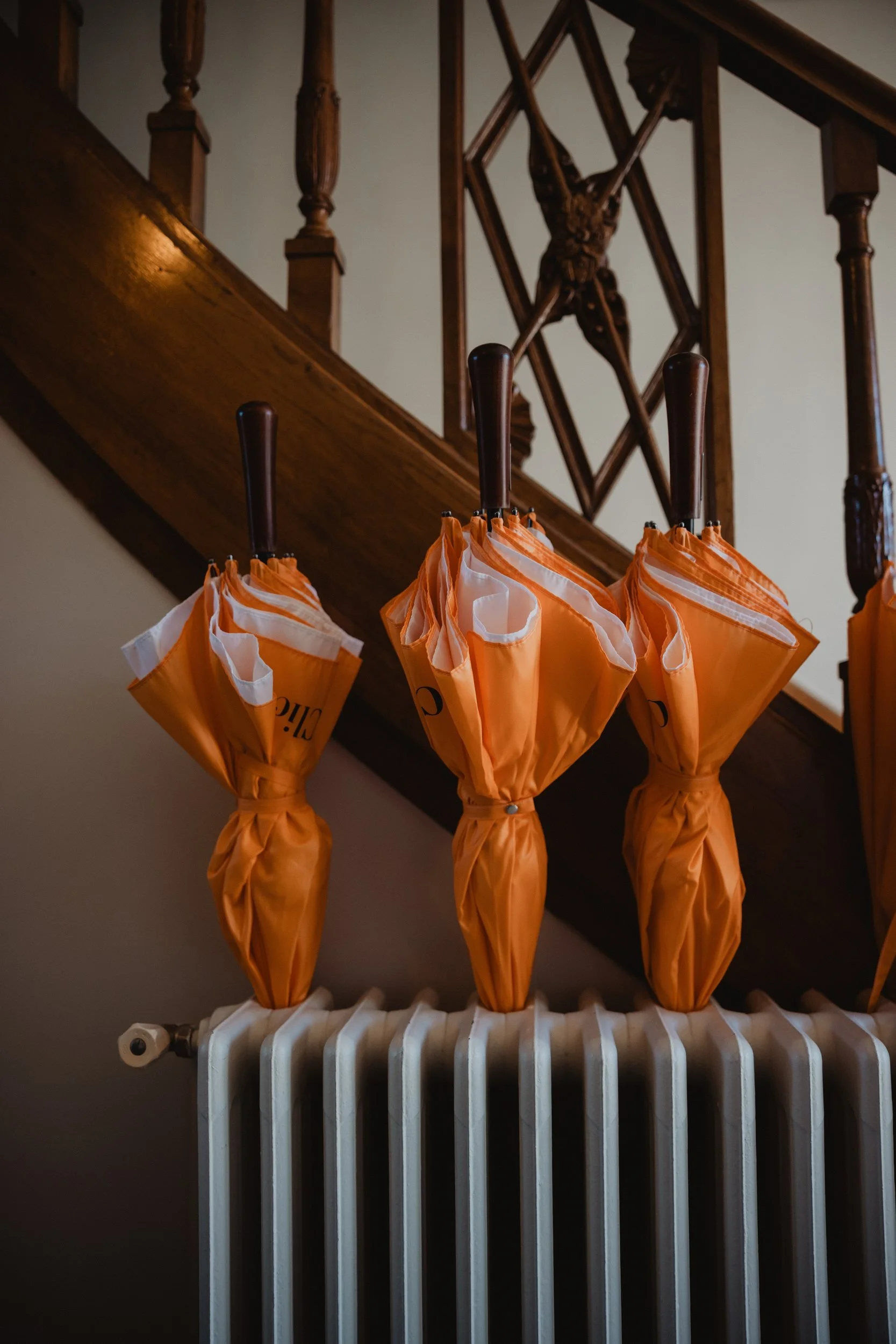 Orange umbrellas hung along a stair rail above a radiator.