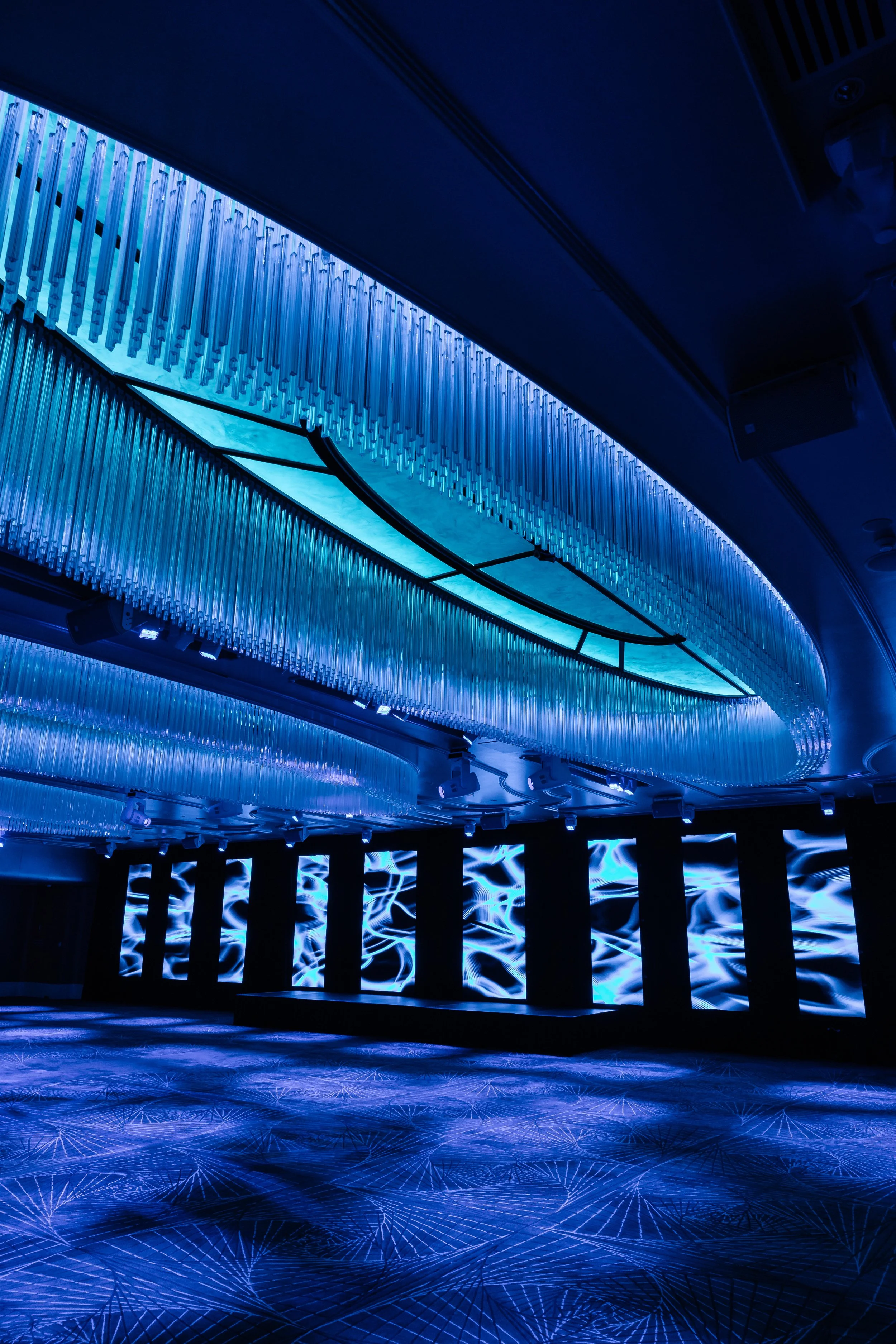 The Grand Ballroom at Shangri-La Hotel, Sydney, lit in blue under the ring chandeliers, with screens along the walls