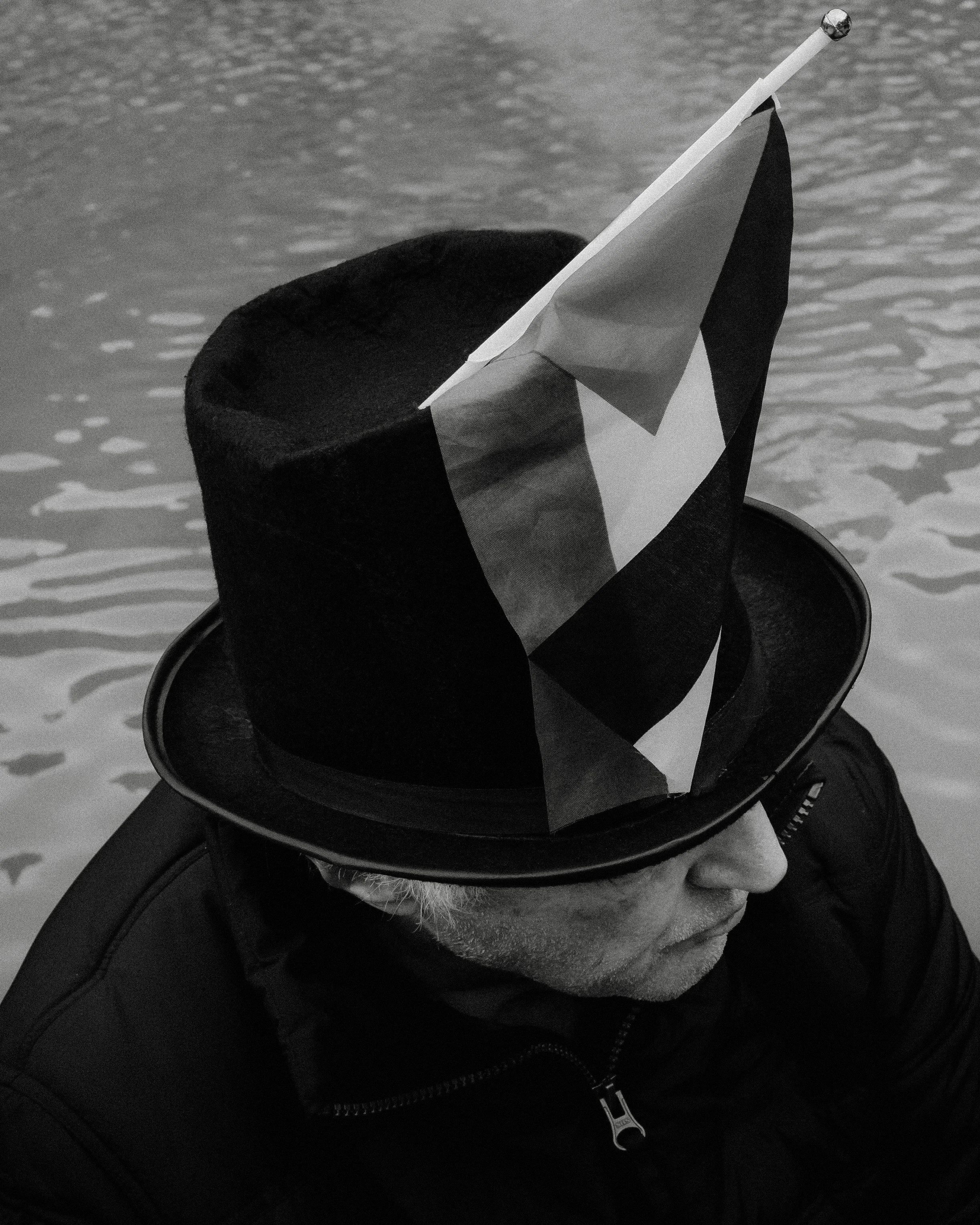 A marcher in a top hat with a small flag, in profile